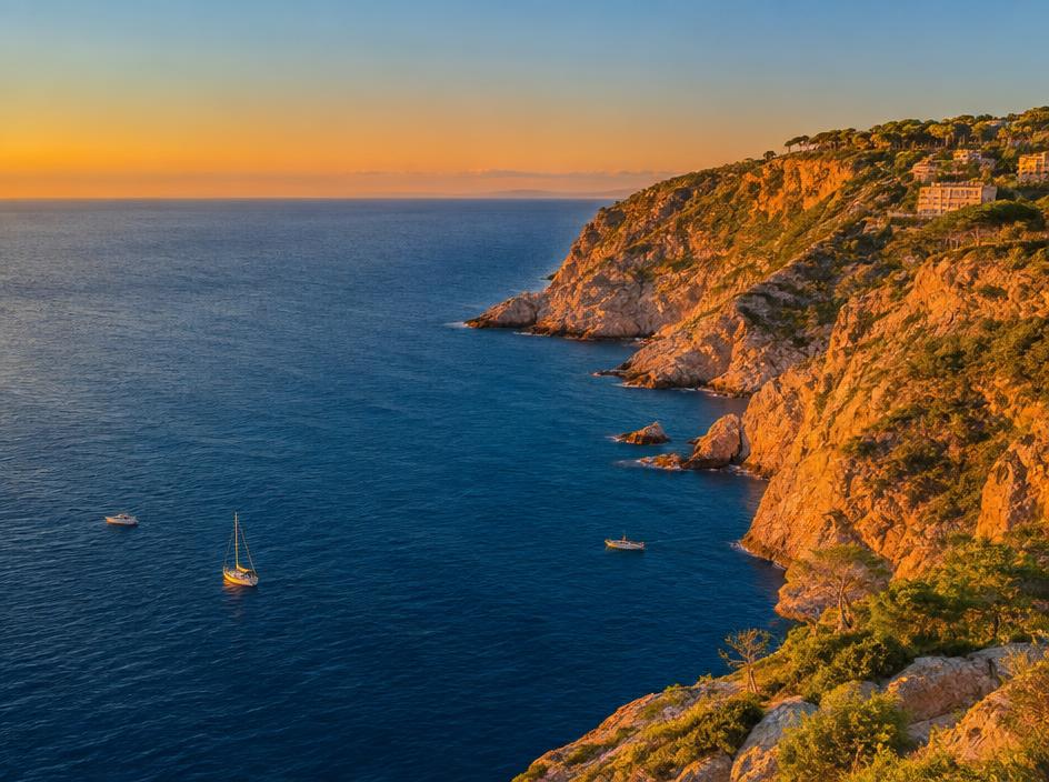 Deep blue sea meeting a warm rocky cliffside at golden hour